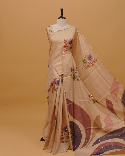 Cream colour Semi Tissue saree featuring Floral Motifs Design and Mirror Work on the body, a Scallop border, and a pallu finished with tassels, paired with a matching blouse piece.