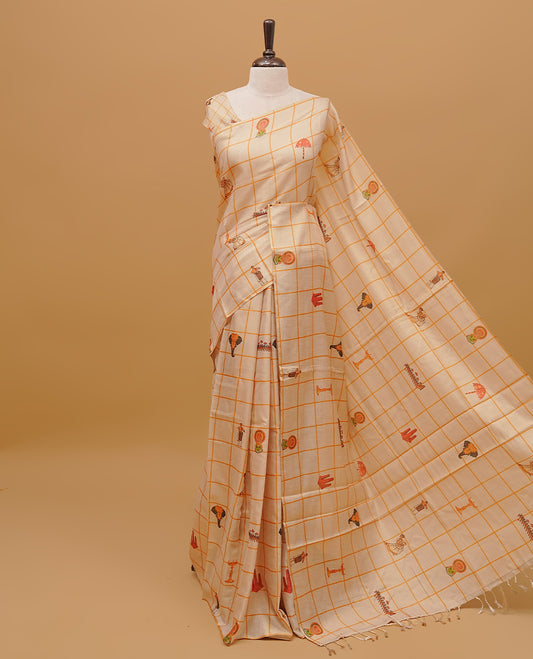 Cream colour semi tissue saree featuring traditional Kerala festival prints in checked body, without a border & pallu finished with tassels. Paired with a matching blouse piece.
