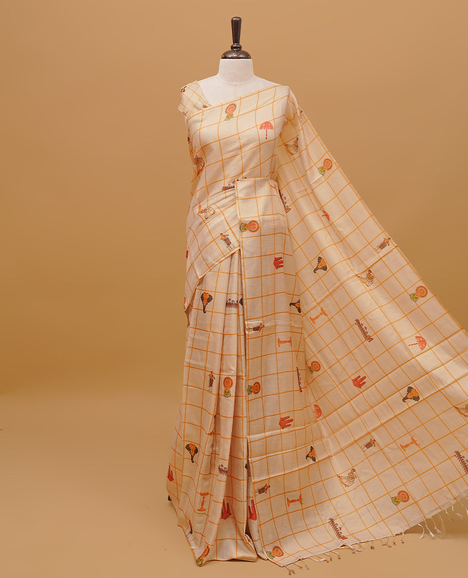 Cream colour semi tissue saree featuring traditional Kerala festival prints in checked body, without a border & pallu finished with tassels. Paired with a matching blouse piece.