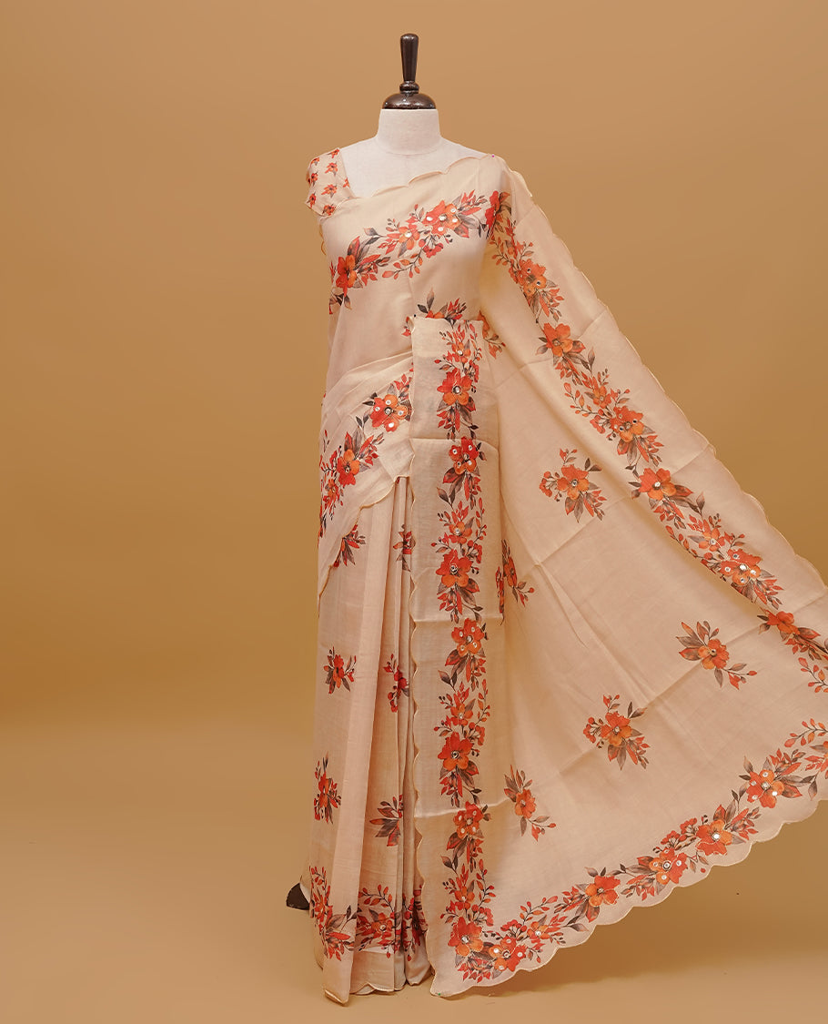 Cream colour semi tissue saree featuring floral prints with Mirror Work on body, with scallop border & pallu finished with tassels. Paired with a matching blouse piece.