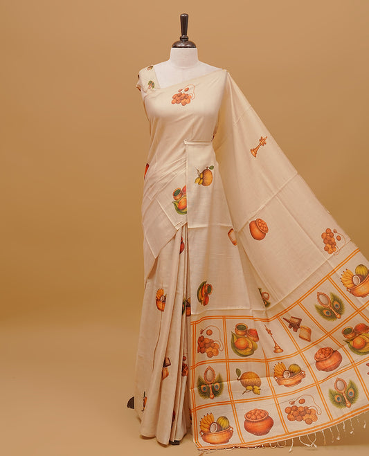Cream colour semi tissue saree featuring Vishu theme prints on the body, without  border & pallu finished with tassels. Paired with a matching blouse piece.
