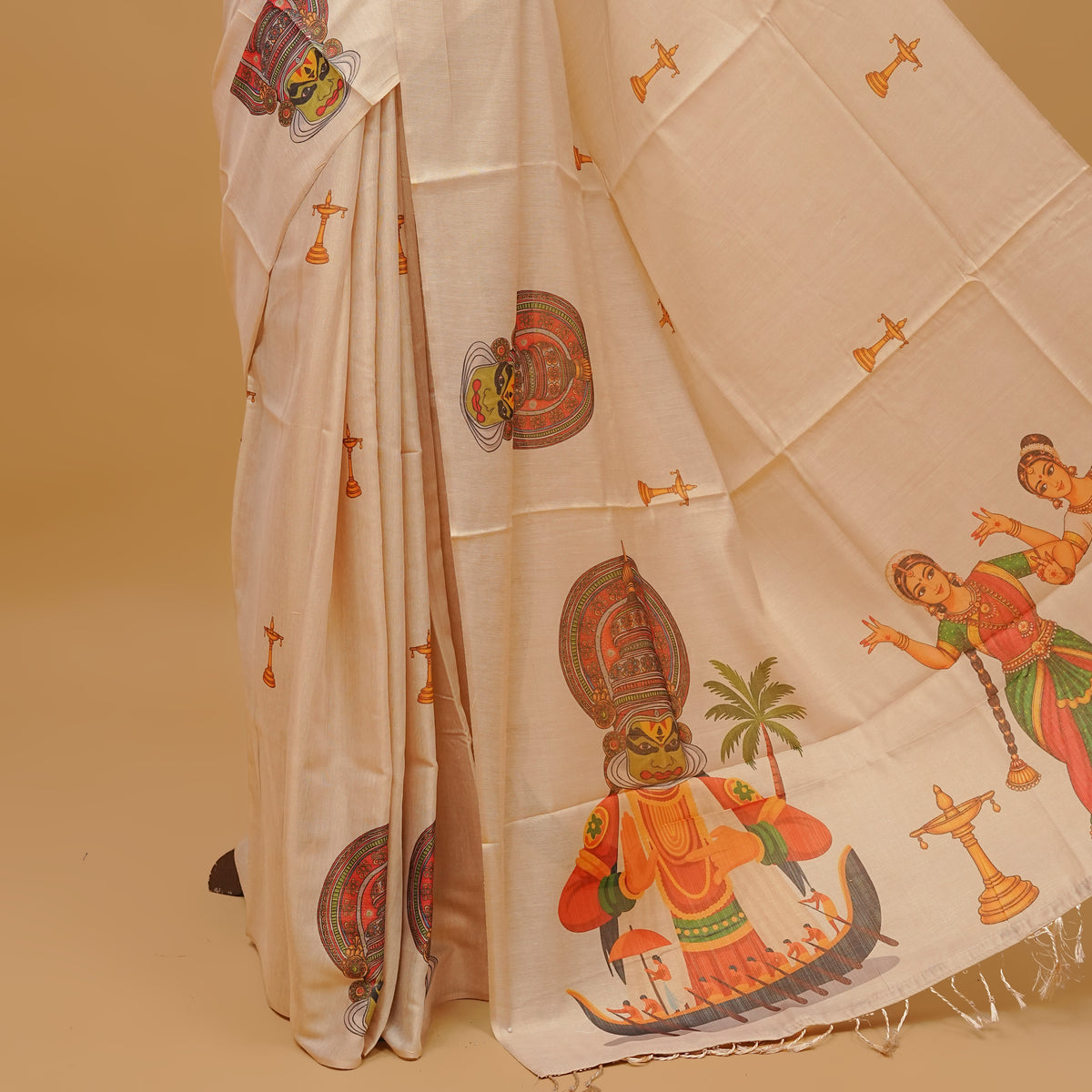 Cream colour semi tissue saree featuring Kerala traditional prints on the body, without  border & pallu finished with tassels. Paired with a matching blouse piece.