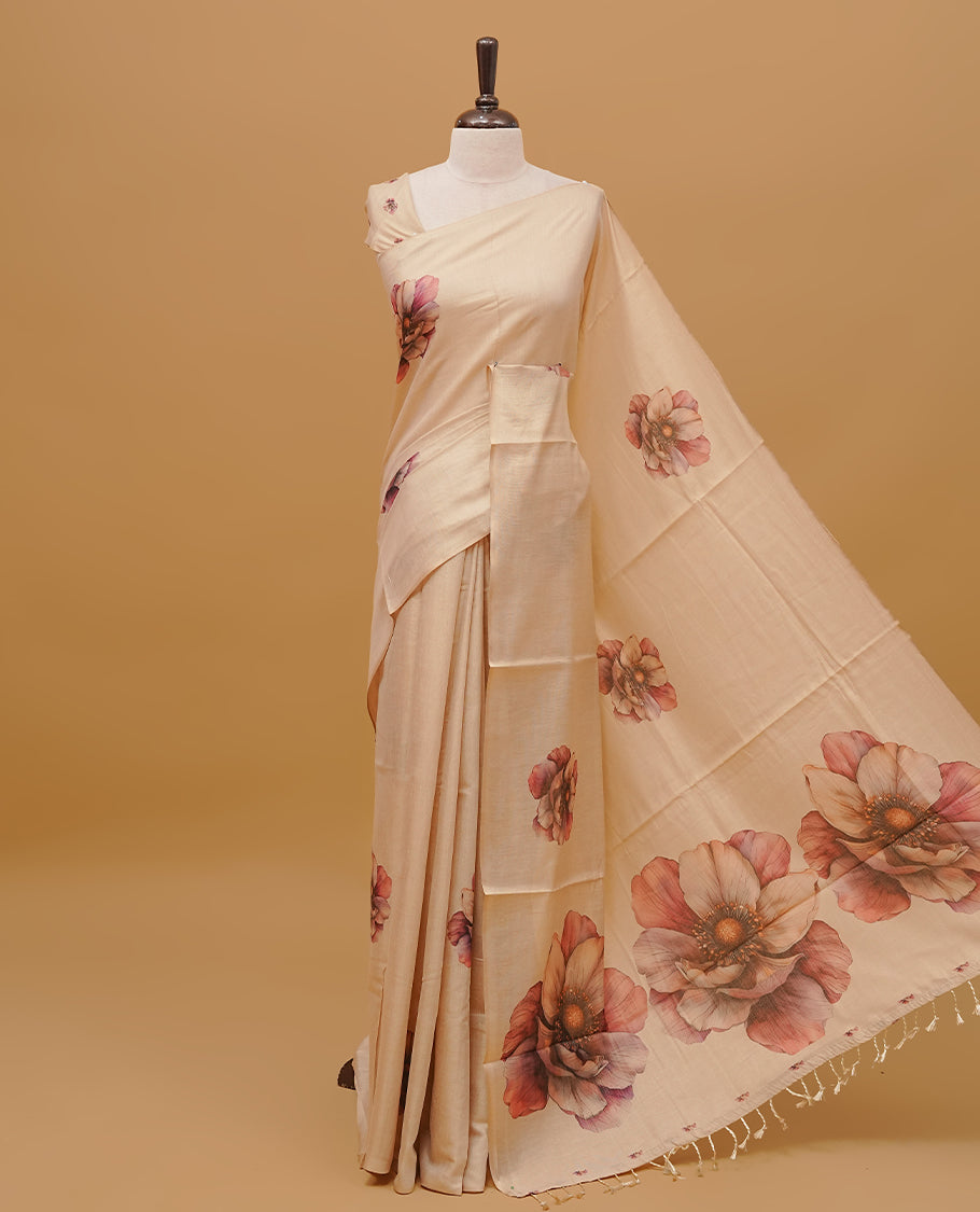 Cream colour semi tissue saree featuring floral prints on body, a borderless design & pallu finished with tassels. Paired with a matching blouse piece.