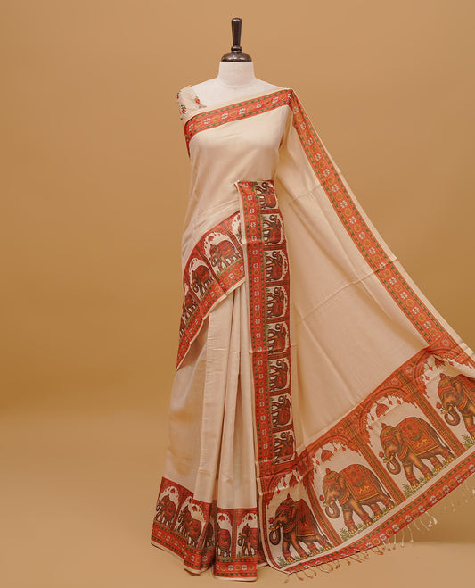 Cream colour semi tissue saree featuring a plain body, Elephant prints on Border & pallu finished with tassels. Paired with a matching blouse piece.