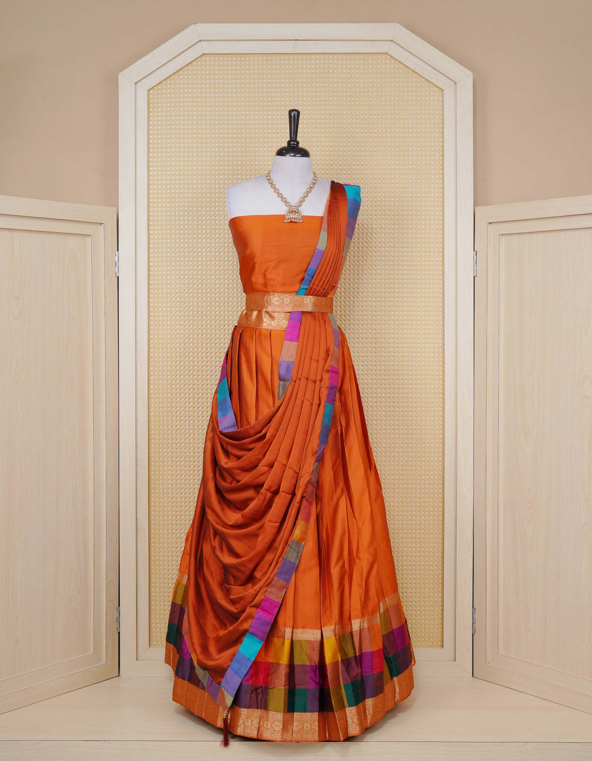 Rust Orange colour Semi Silk Semi stitched dhavani set featuring a Plain body with a matching Multi colour with gold zari bordered skirt & blouse piece and dupatta.