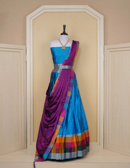 Peacock Blue colour Semi Silk Semi stitched dhavani set featuring a Plain body with a matching Multi colour with gold zari bordered skirt & blouse piece and dupatta.