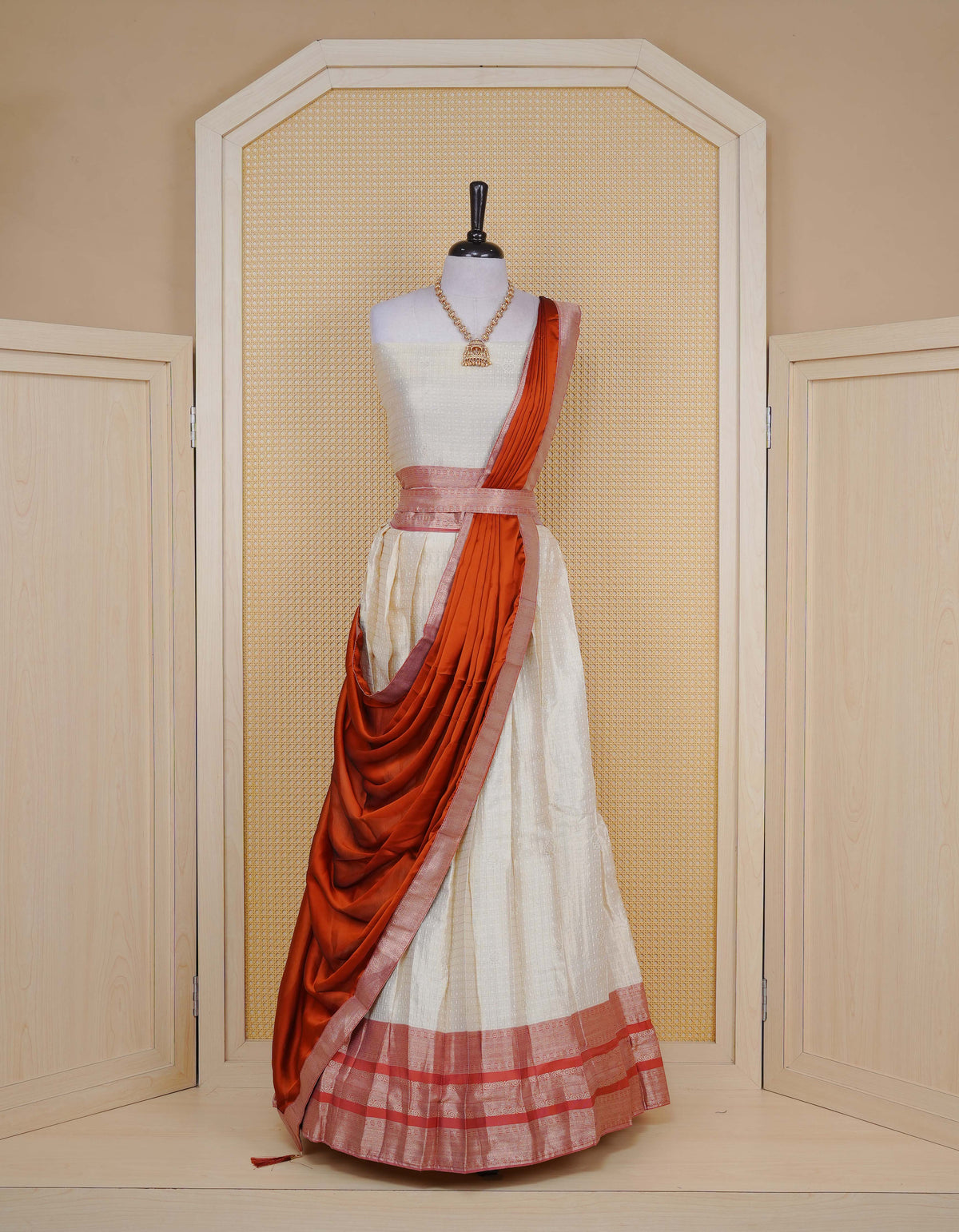 Cream colour Semi Silk Semi stitched dhavani set featuring Gold zari check pattern with motifs on body ,contrast Peach colour with gold zari bordered skirt, paired with matching blouse piece & dupatta.