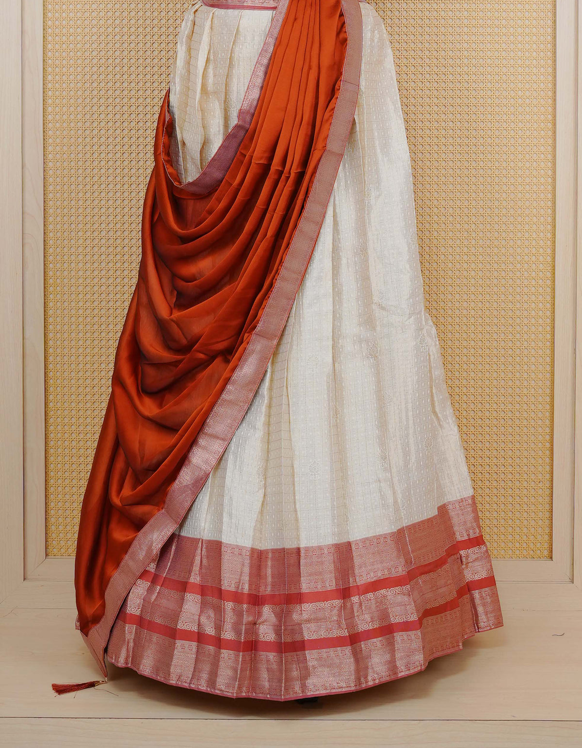 Cream colour Semi Silk Semi stitched dhavani set featuring Gold zari check pattern with motifs on body ,contrast Peach colour with gold zari bordered skirt, paired with matching blouse piece & dupatta.