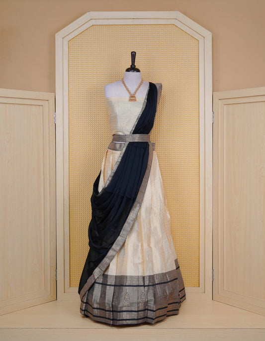 Cream colour Semi Silk Semi stitched dhavani set featuring Gold zari check pattern with motifs on body ,contrast Black colour with gold zari bordered skirt, paired with matching blouse piece & dupatta