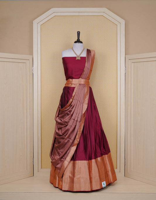 Maroon colour Semi Silk Semi stitched dhavani set featuring a Plain body with a matching contrast copper colour with gold zari bordered skirt & blouse piece and dupatta.