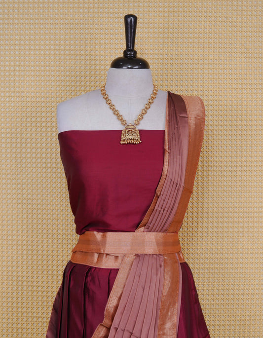 Maroon colour Semi Silk Semi stitched dhavani set featuring a Plain body with a matching contrast copper colour with gold zari bordered skirt & blouse piece and dupatta.