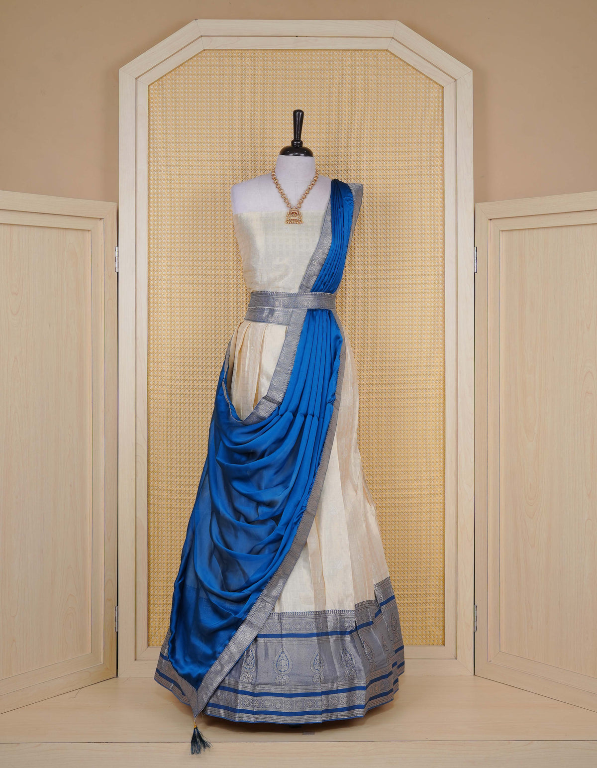 Cream colour tissue semi stitched dhavani set featuring gold zari Check patterns with motifs on the body and a matching Contrast Blue colour with  gold zari bordered skirt & blouse piece and dupatta.