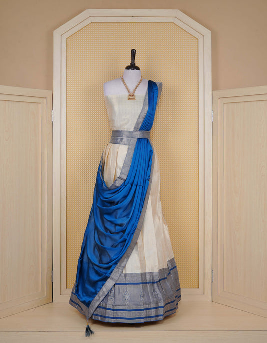 Cream colour tissue semi stitched dhavani set featuring gold zari Check patterns with motifs on the body and a matching Contrast Blue colour with  gold zari bordered skirt & blouse piece and dupatta.