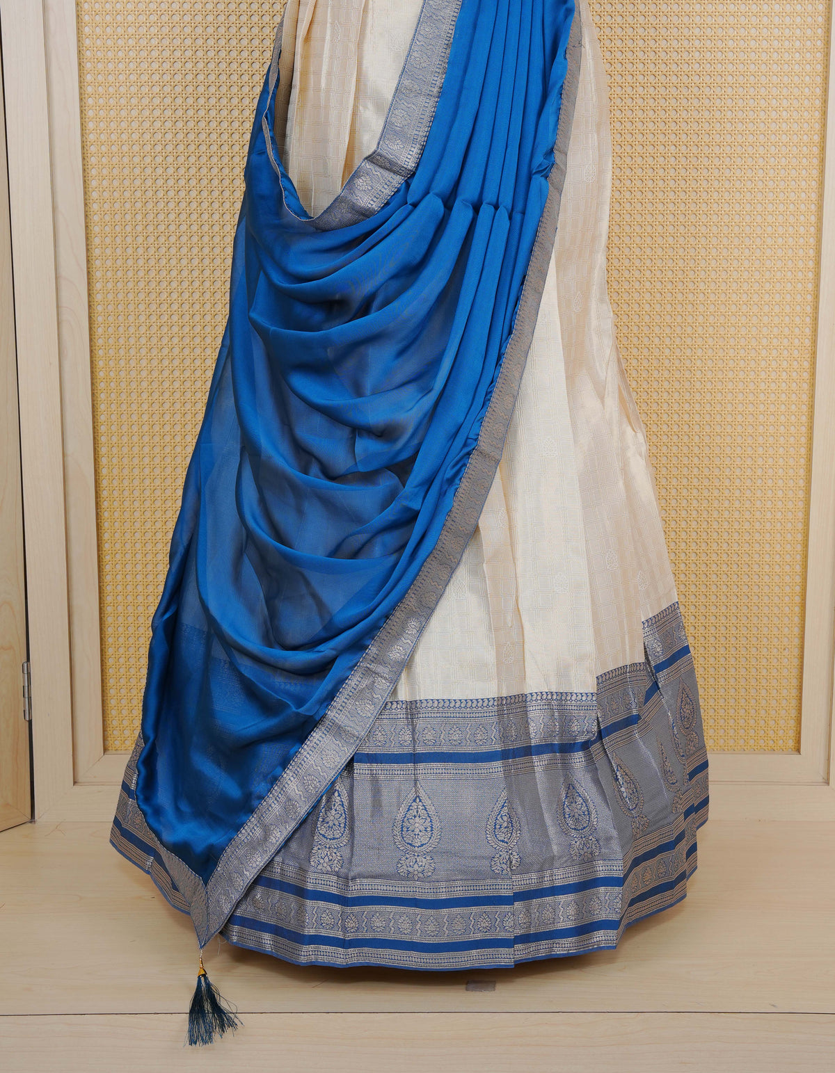 Cream colour tissue semi stitched dhavani set featuring gold zari Check patterns with motifs on the body and a matching Contrast Blue colour with  gold zari bordered skirt & blouse piece and dupatta.