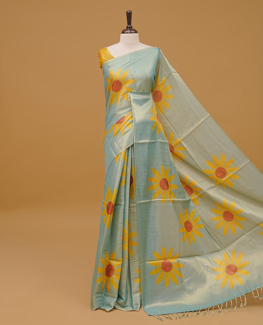 Mint colour Semi Tissue saree featuring a yellow floral prints on body, Without border & pallu finished with tassels. Paired with a matching blouse piece.