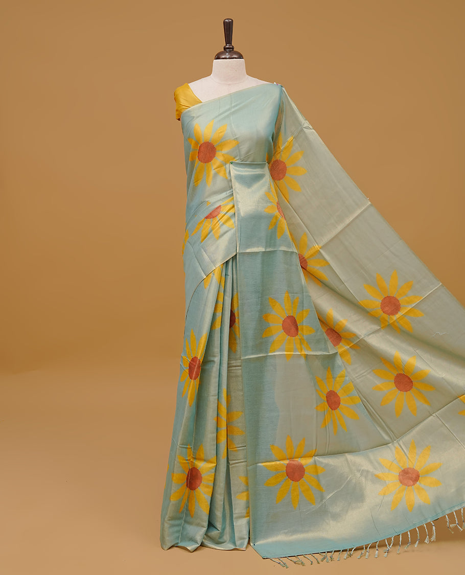 Mint colour Semi Tissue saree featuring a yellow floral prints on body, Without border & pallu finished with tassels. Paired with a matching blouse piece.