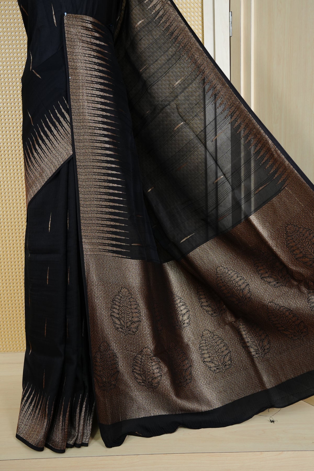 Black colour semi banaras tussar georgette saree featuring gold zari pattern on body, finished with gold zari temple border and paired with matching blouse piece.
