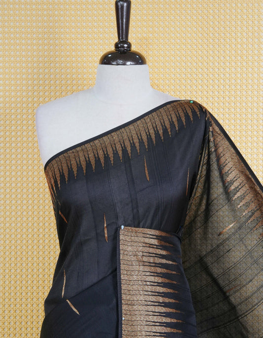 Black colour semi banaras tussar georgette saree featuring gold zari pattern on body, finished with gold zari temple border and paired with matching blouse piece.