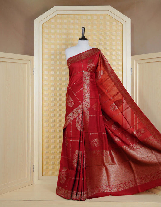 Brick red colour semi banaras tussar georgette saree featuring gold zari floral pattern on body, finished with gold zari floral motifs on border and paired with matching blouse piece.