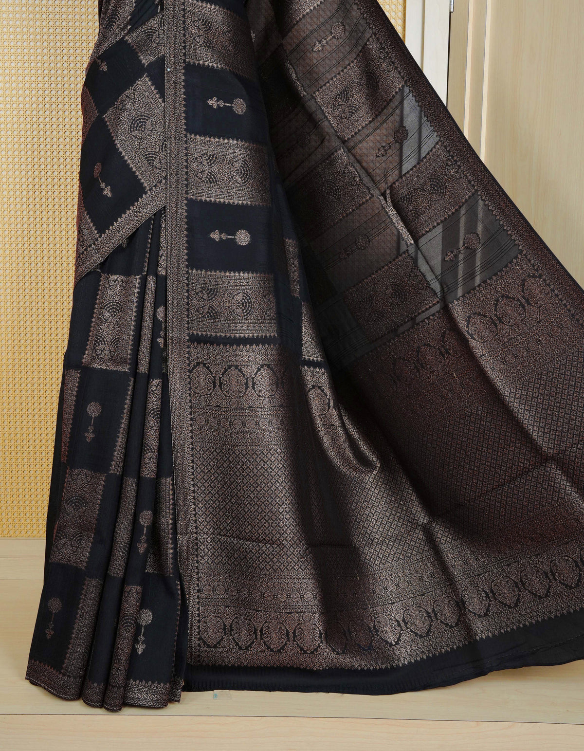 Black colour semi banaras tussar georgette saree featuring gold zari box pattern with motifs on body, finished with gold zari fancy border and paired with matching blouse piece.