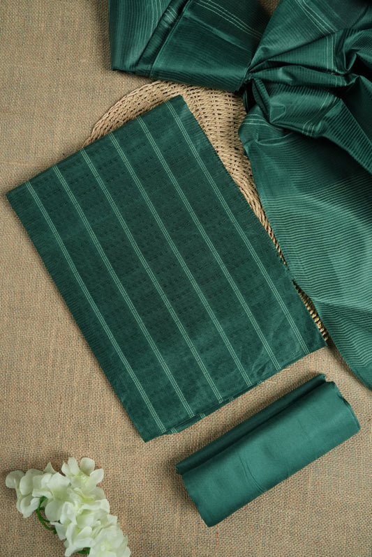 Dark Turquoise green colour tussar suit material featuring a subtle self woven pattern and vertical lines on the body, paired with a lightweight matching dupatta with tassel edges and a plain bottom piece.