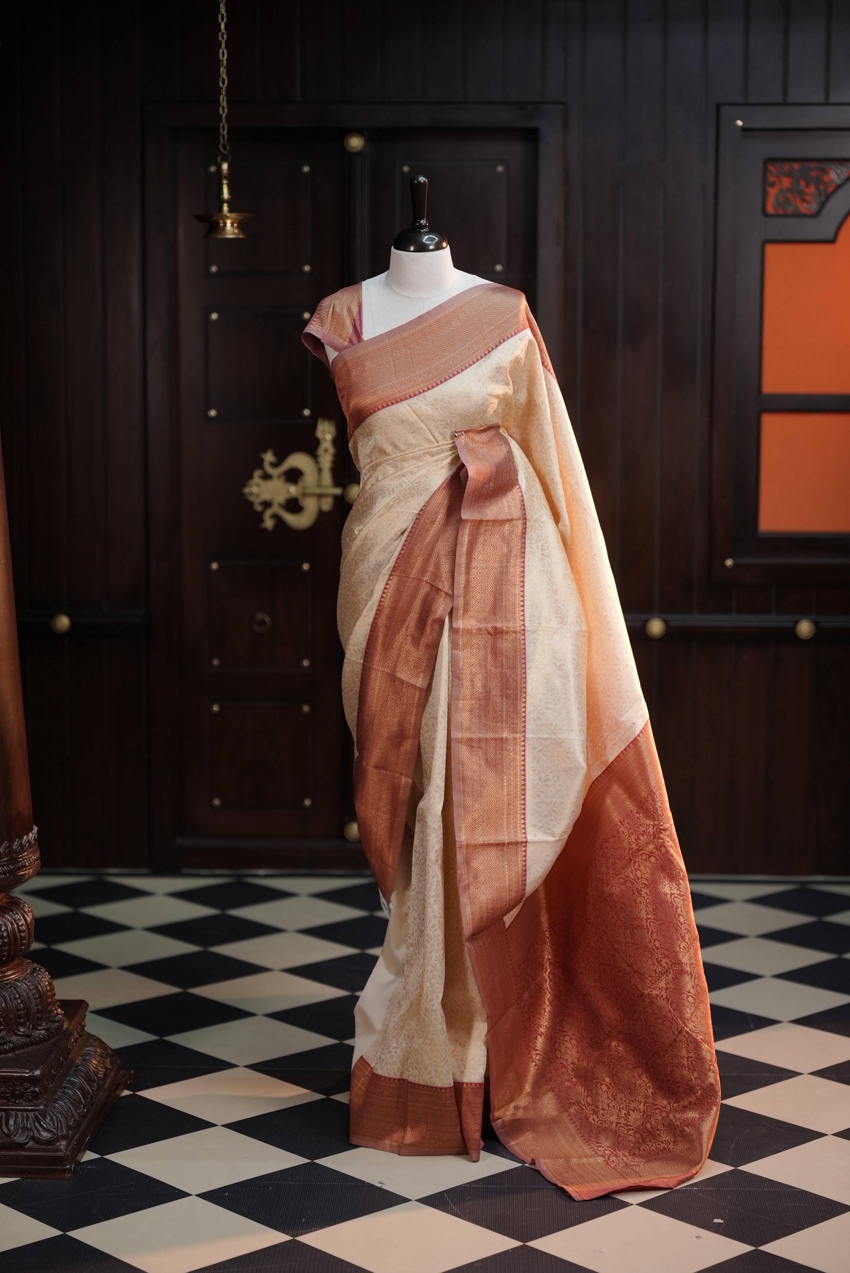 Cream colour semi tissue saree highlighting golden thread worked body, contrast maroon colour border, pallu and comes with matching blouse piece.