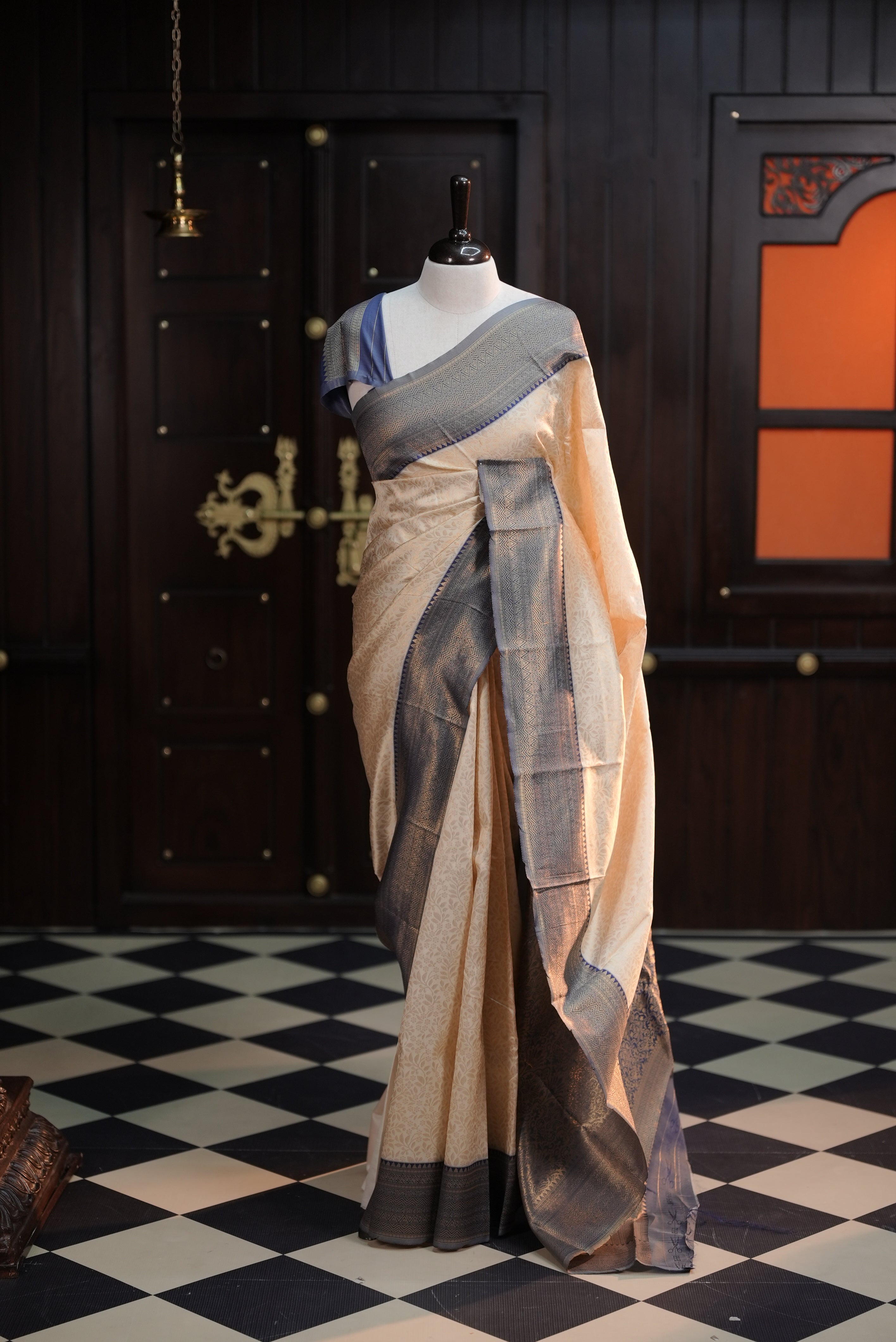 Cream colour semi tissue saree highlighting golden thread worked body, contrast blue colour border, pallu and comes with matching blouse piece.