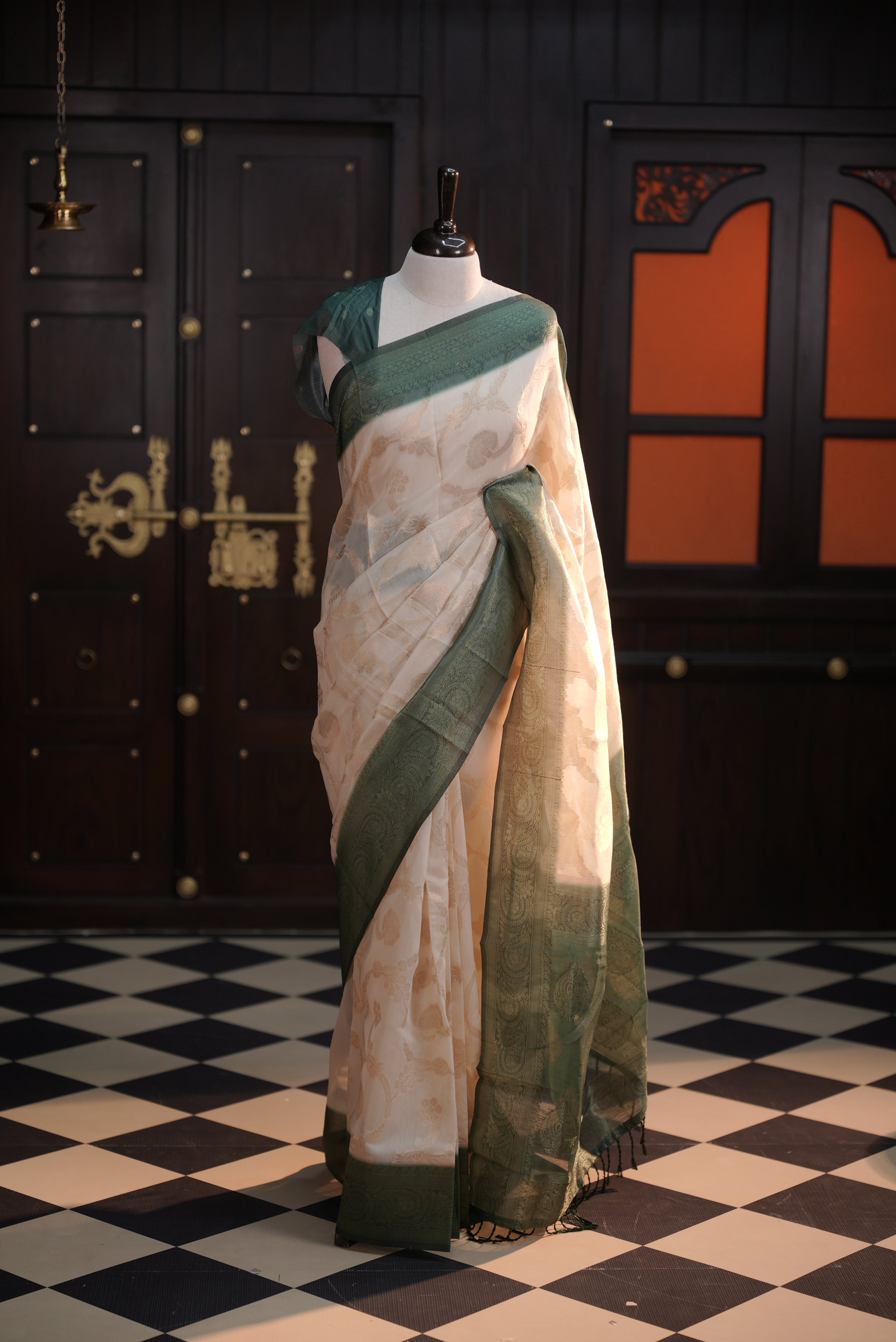 Cream colour Litchi silk saree highlighting antique floral thread pattern on body, contrast Green colour border, pallu and comes with matching blouse piece.