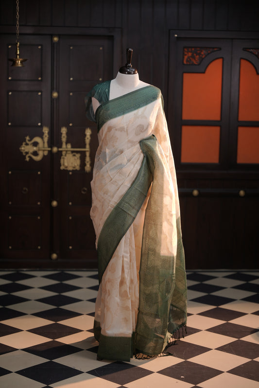 Cream colour Litchi silk saree highlighting antique floral thread pattern on body, contrast Green colour border, pallu and comes with matching blouse piece.