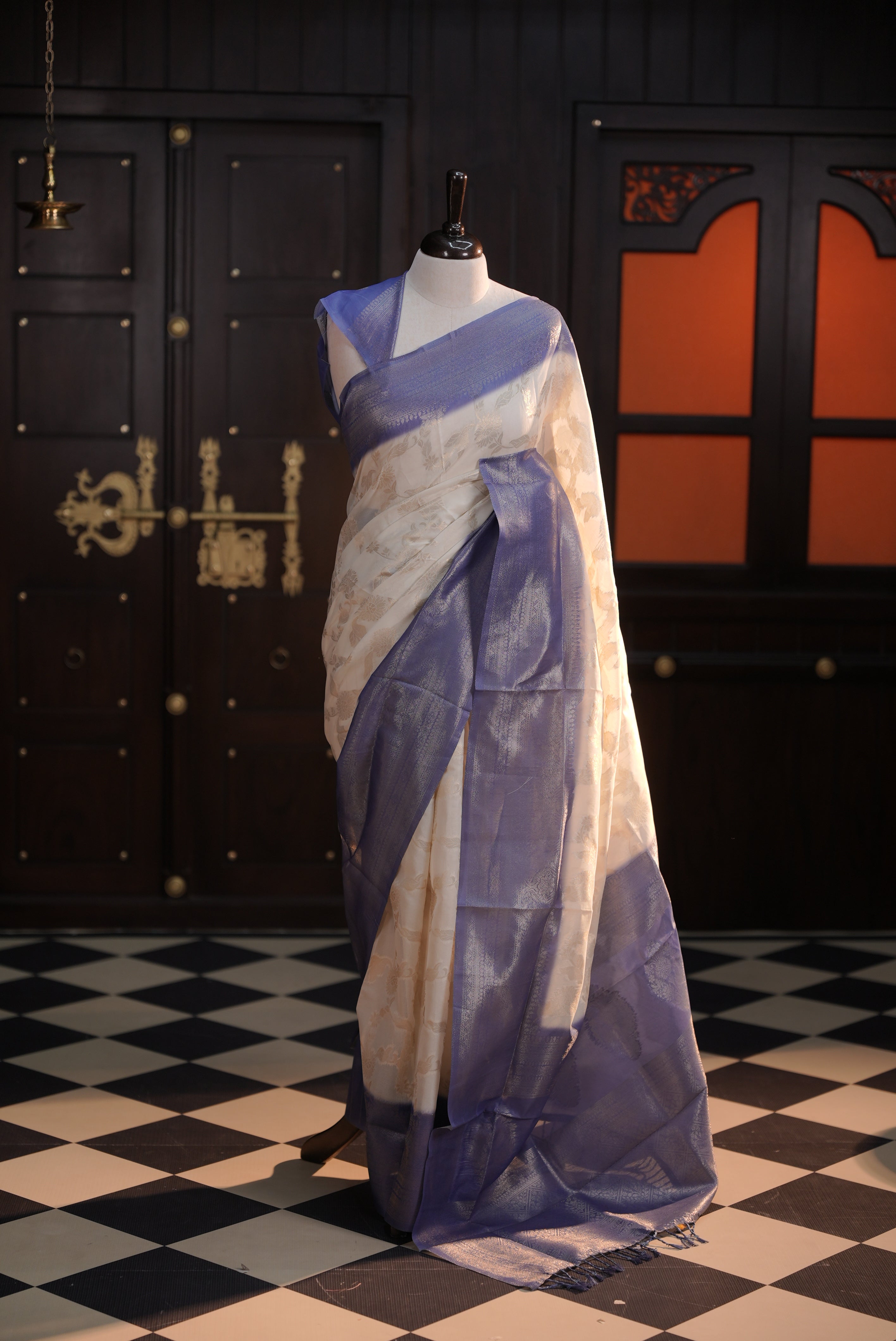 Cream colour Litchi silk saree highlighting antique floral thread pattern on body, contrast Blue colour border, pallu and comes with matching blouse piece.