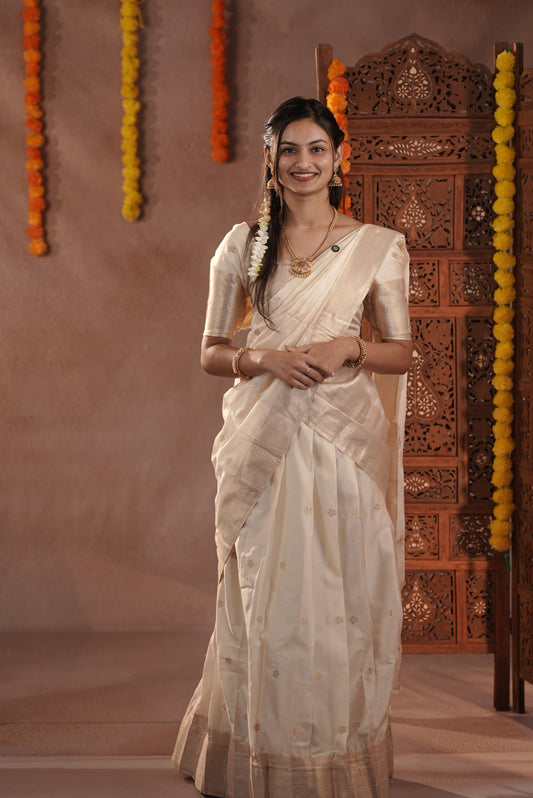 Off white colour Semi Stitched Tissue Banaras Dhavani Set Featuring Skirt with Gold zari buttas & Traditional border, paired with Cream Blouse material with gold zari buttas, finishing with same colour with gold zari buttas & scallop border Dupatta.