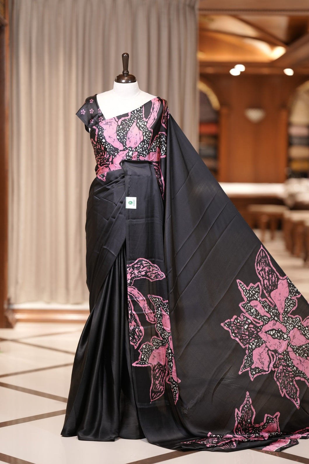 Black colour modal satin saree featuring soft satin touch fabric with bold Pink colour floral prints across the body and matching pallu & Comes with a coordinated floral printed blouse for a chic, graceful look