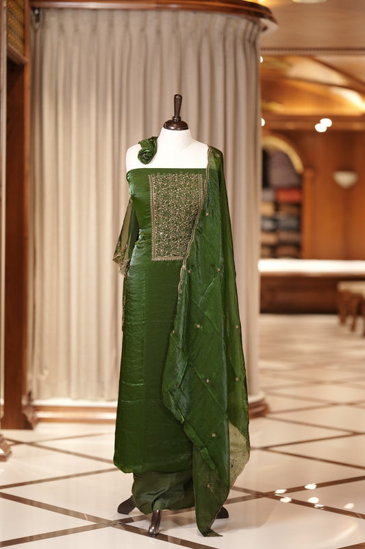 Green colour Semi silk Salwar suit featuring rich golden zari and sequin work on the floral designed neckline, scallop border, and delicate floral motifs on the dupatta & paired with a plain bottom.