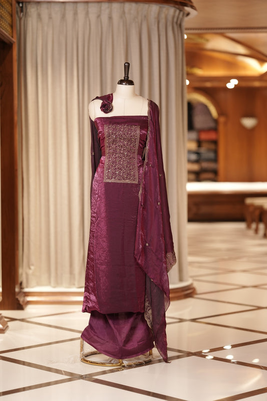 Wine colour Semi silk Salwar suit featuring rich golden zari and sequin work on the floral designed neckline, scallop border, and delicate floral motifs on the dupatta & paired with a plain bottom.