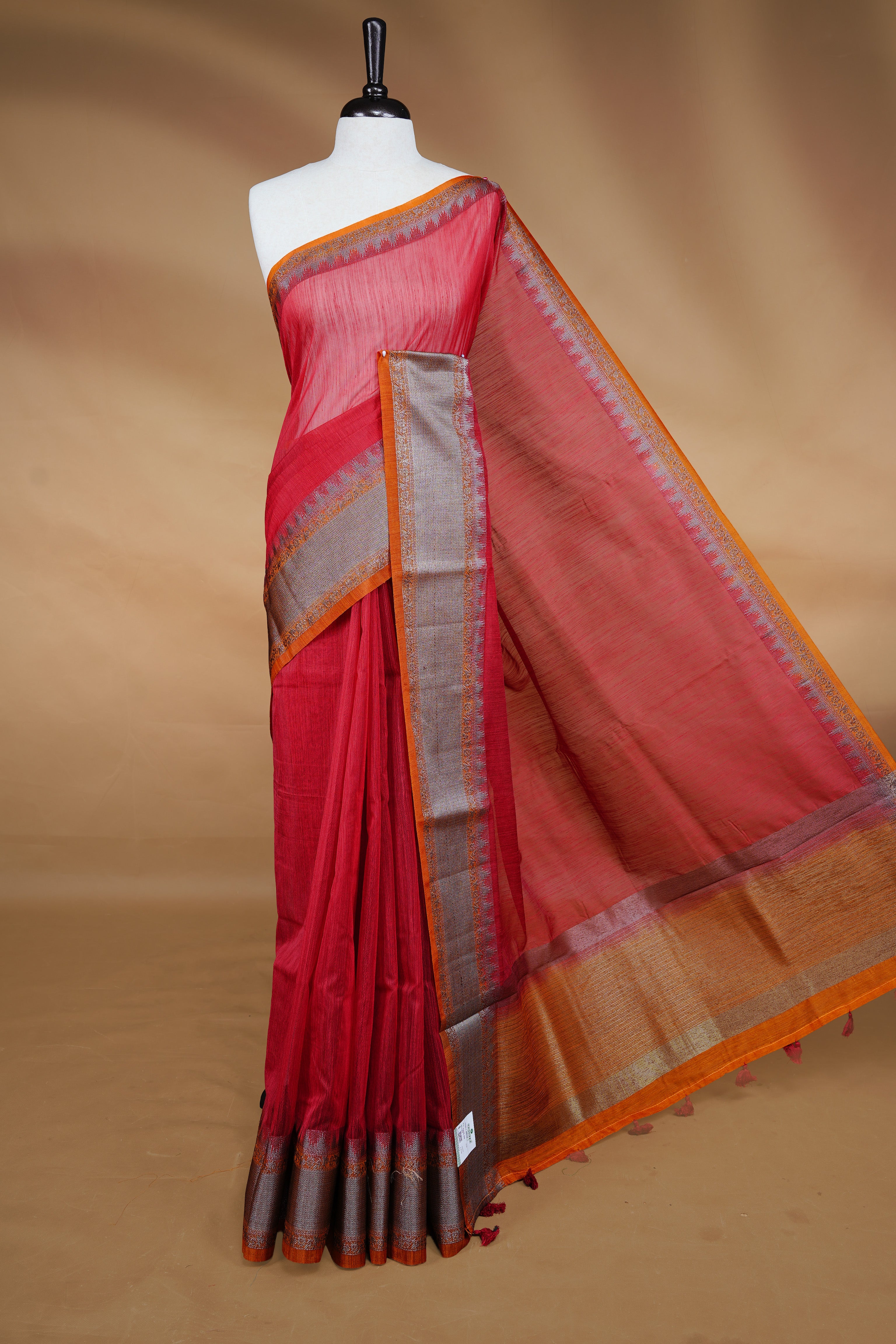 Red colour Semi linen saree featuring Elegant plain body, complemented by contrast Orange colour With Antique zari border, paired with matching blouse piece.