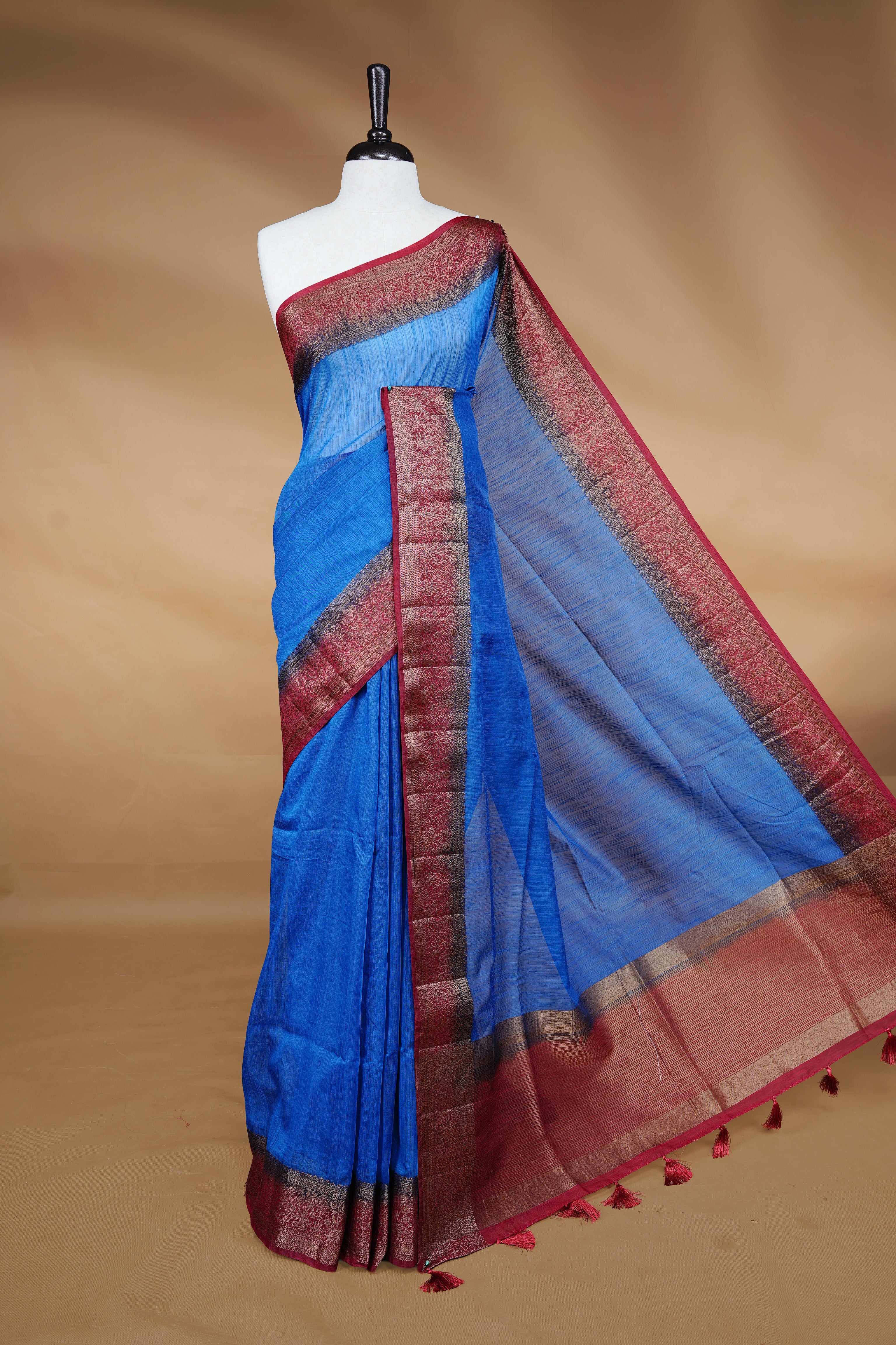 Blue colour Semi linen saree featuring Elegant plain body, complemented by contrast Maroon colour With Antique zari border, paired with matching blouse piece.