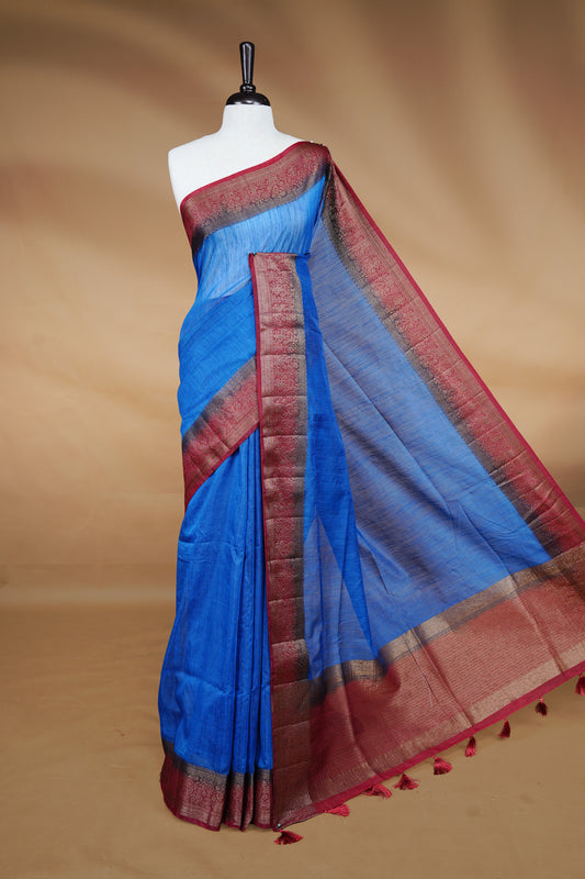 Blue colour Semi linen saree featuring Elegant plain body, complemented by contrast Maroon colour With Antique zari border, paired with matching blouse piece.