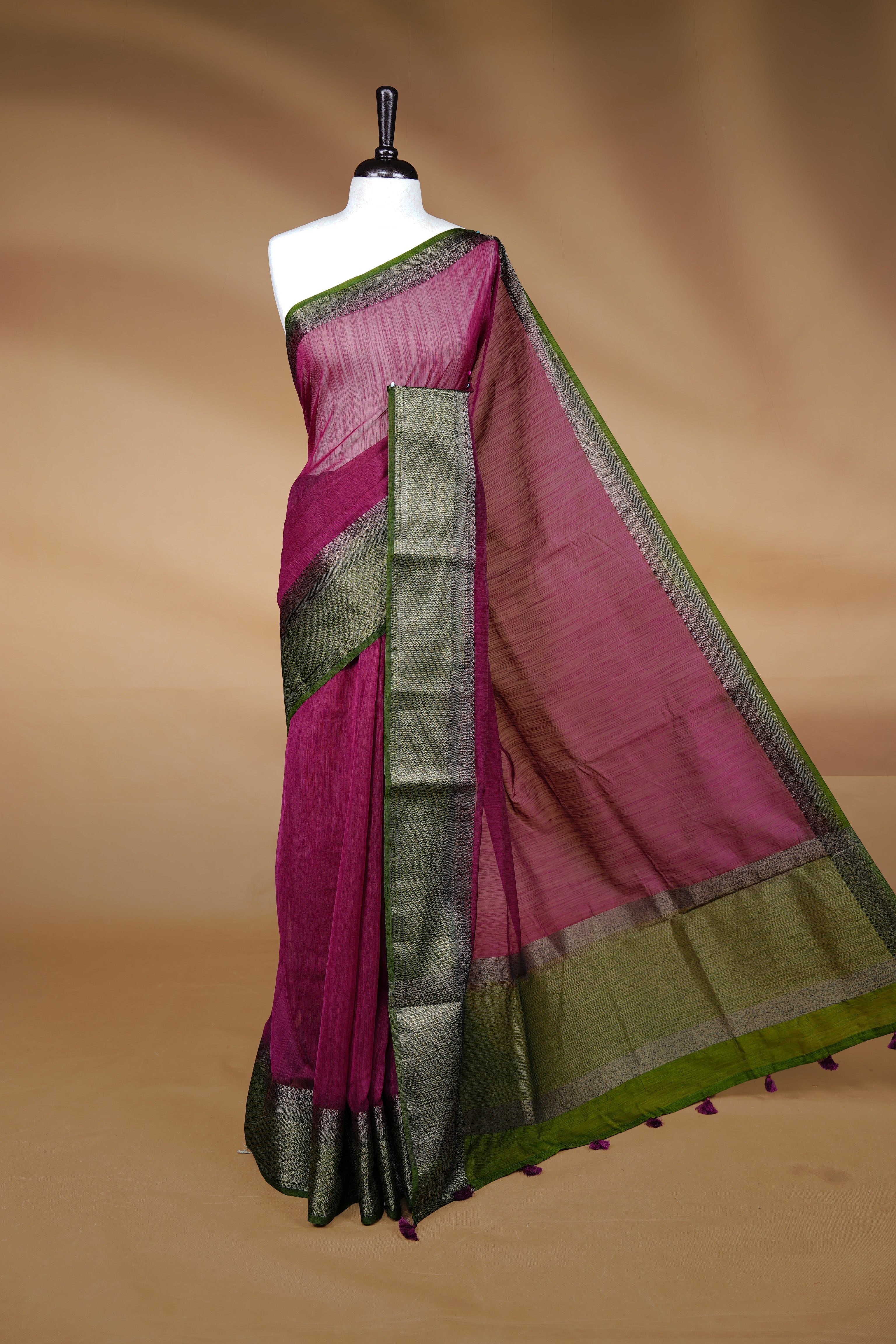 Burgundy colour Semi linen saree featuring Elegant plain body, complemented by contrast Green colour With Antique zari border, paired with matching blouse piece.