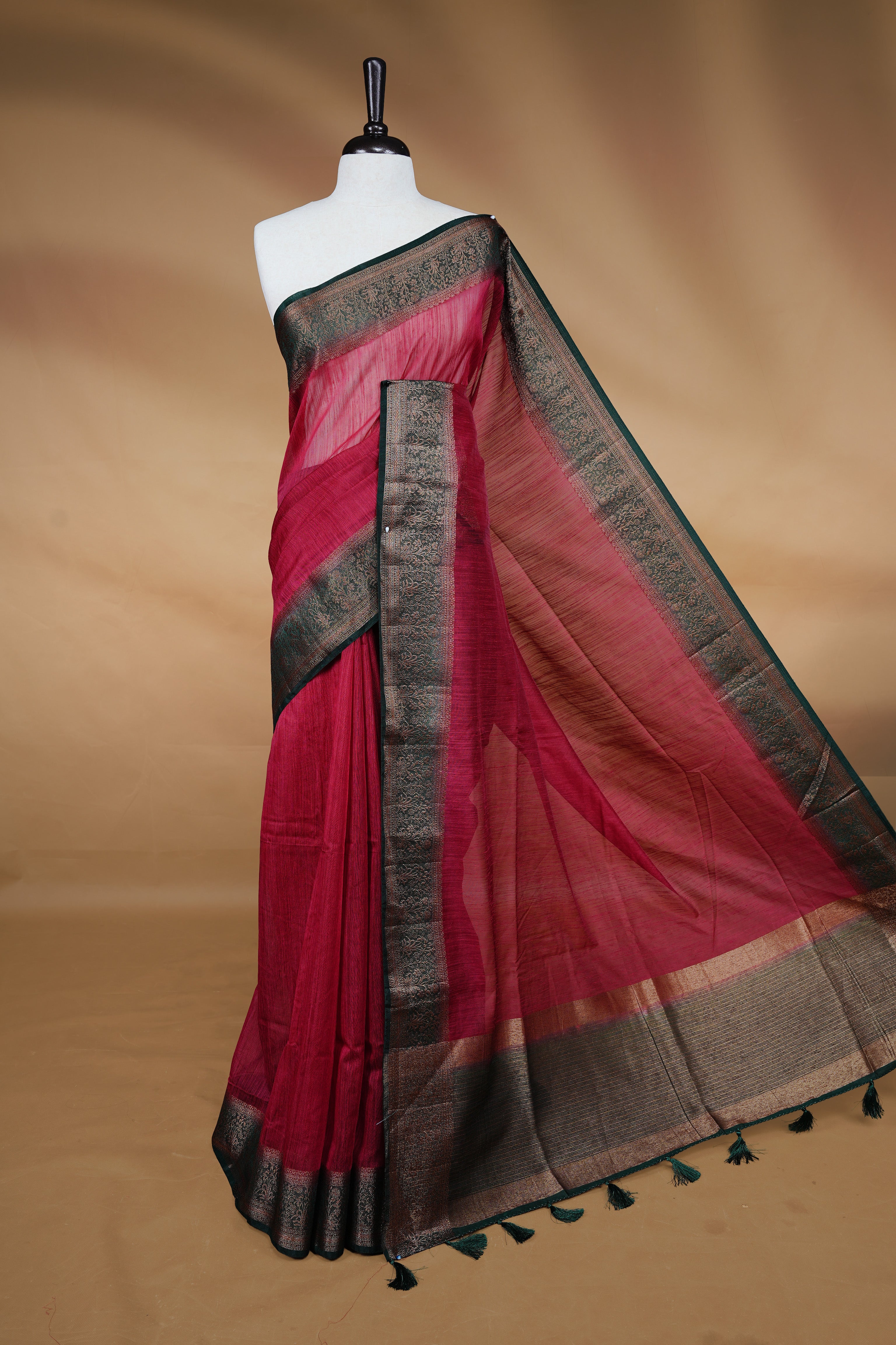 Maroon colour Semi linen saree featuring Elegant plain body, complemented by contrast Green colour With Antique zari border, paired with matching blouse piece.