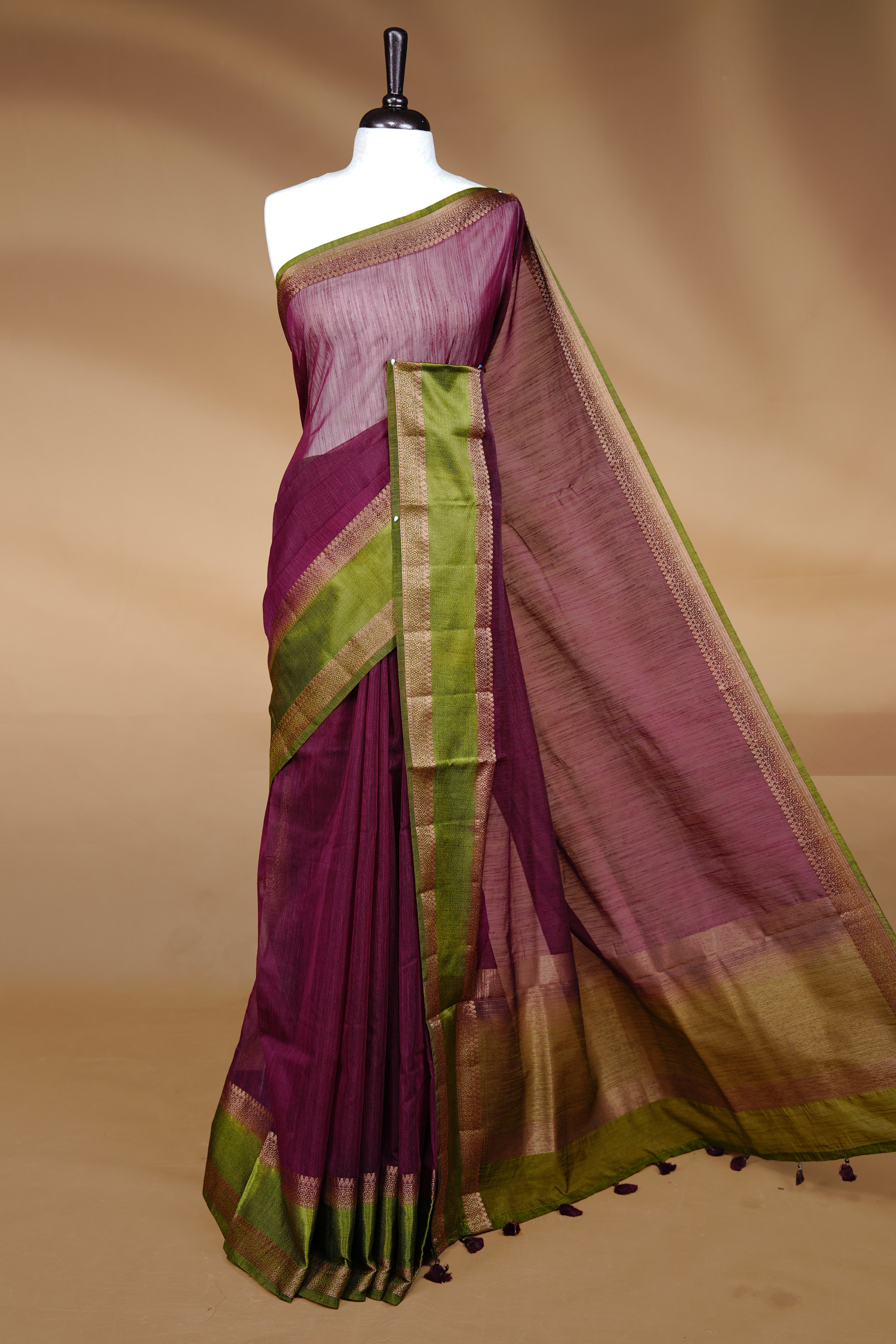 Maroon colour Semi linen saree featuring Elegant plain body, complemented by contrast Green colour With Antique zari border, paired with matching blouse piece.