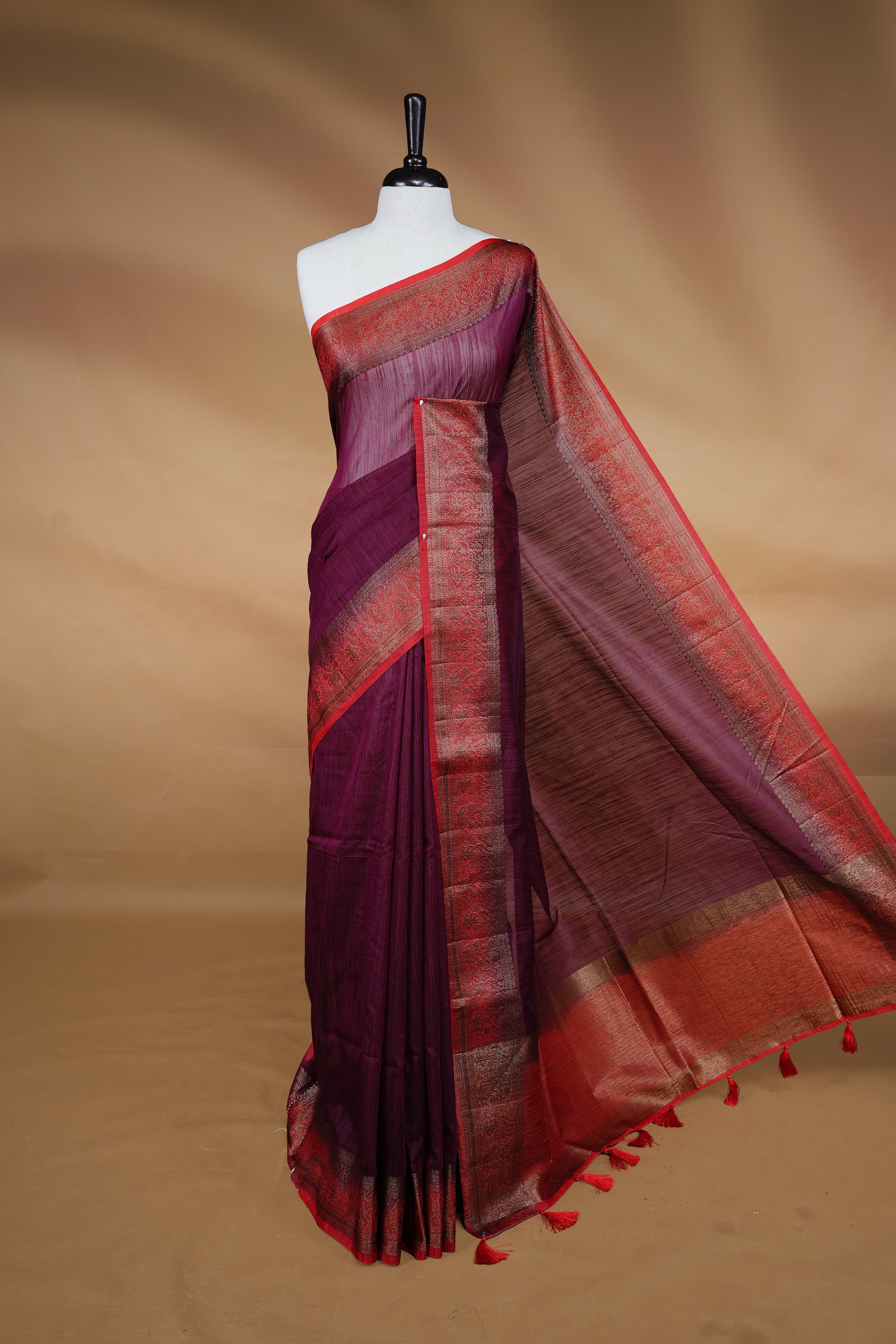 Maroon colour Semi linen saree featuring Elegant plain body, complemented by contrast Red colour With Antique zari border, paired with matching blouse piece.