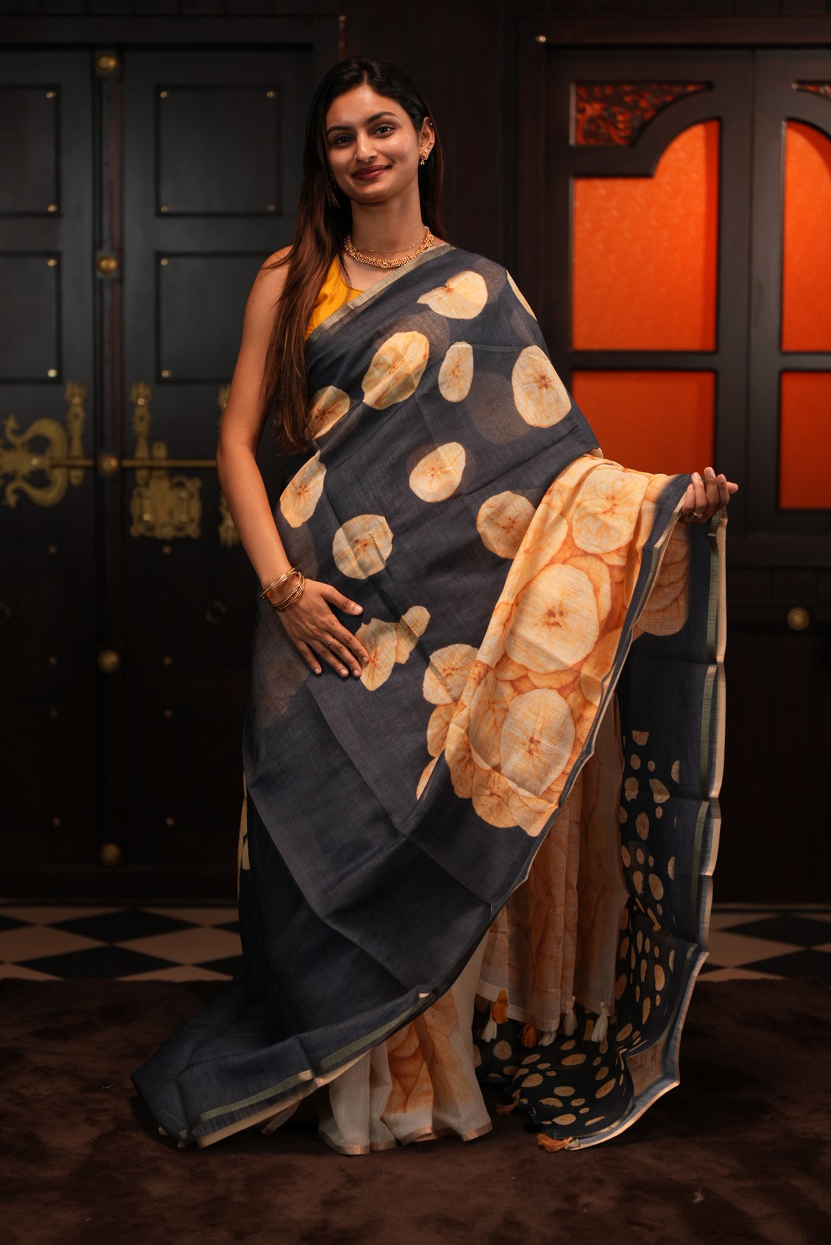 Black colour Semi Linen saree featuring Banana Chips Print with Gold Tissue Border, comes with tassels.