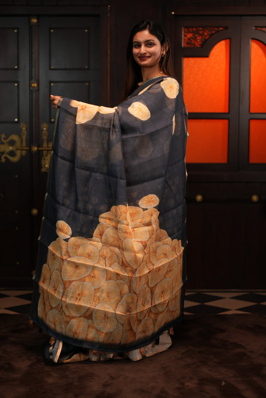Black colour Semi Linen saree featuring Banana Chips Print with Gold Tissue Border, comes with tassels.