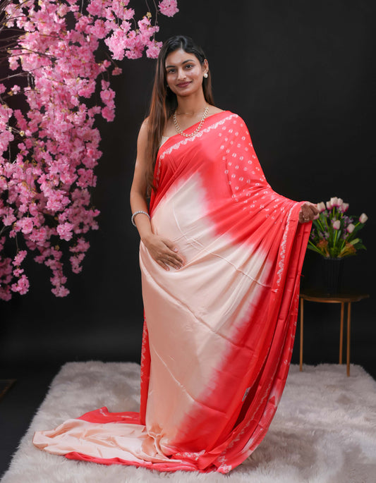 Light Pink coloured modal satin saree featuring a plain cream coloured body, complemented by a double shaded border and a Bandhani designed pallu with jhumka tassels. Paired with a matching contrast coloured blouse piece.