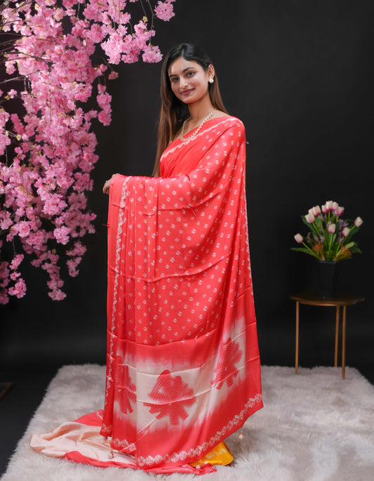 Light Pink coloured modal satin saree featuring a plain cream coloured body, complemented by a double shaded border and a Bandhani designed pallu with jhumka tassels. Paired with a matching contrast coloured blouse piece.