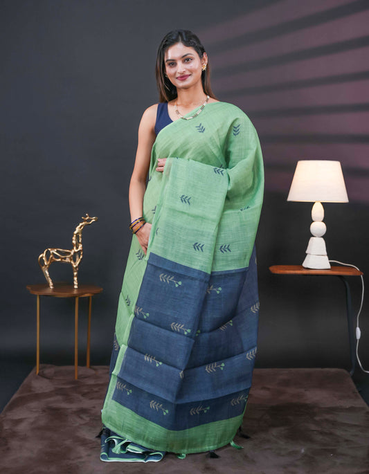 Pista Green and black half and half semi linen saree having leaf and floral prints on body, contast colour printed pallu with tassels comes with matching Blouse Piece