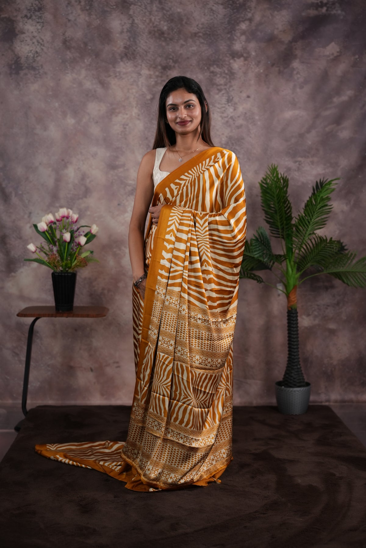 Mustard Yellow Colour satin model saree featuring Zibra print on body. Ajrak & zibra print on pallu with jhumka tassels, comes with contrast plain blouse piece.