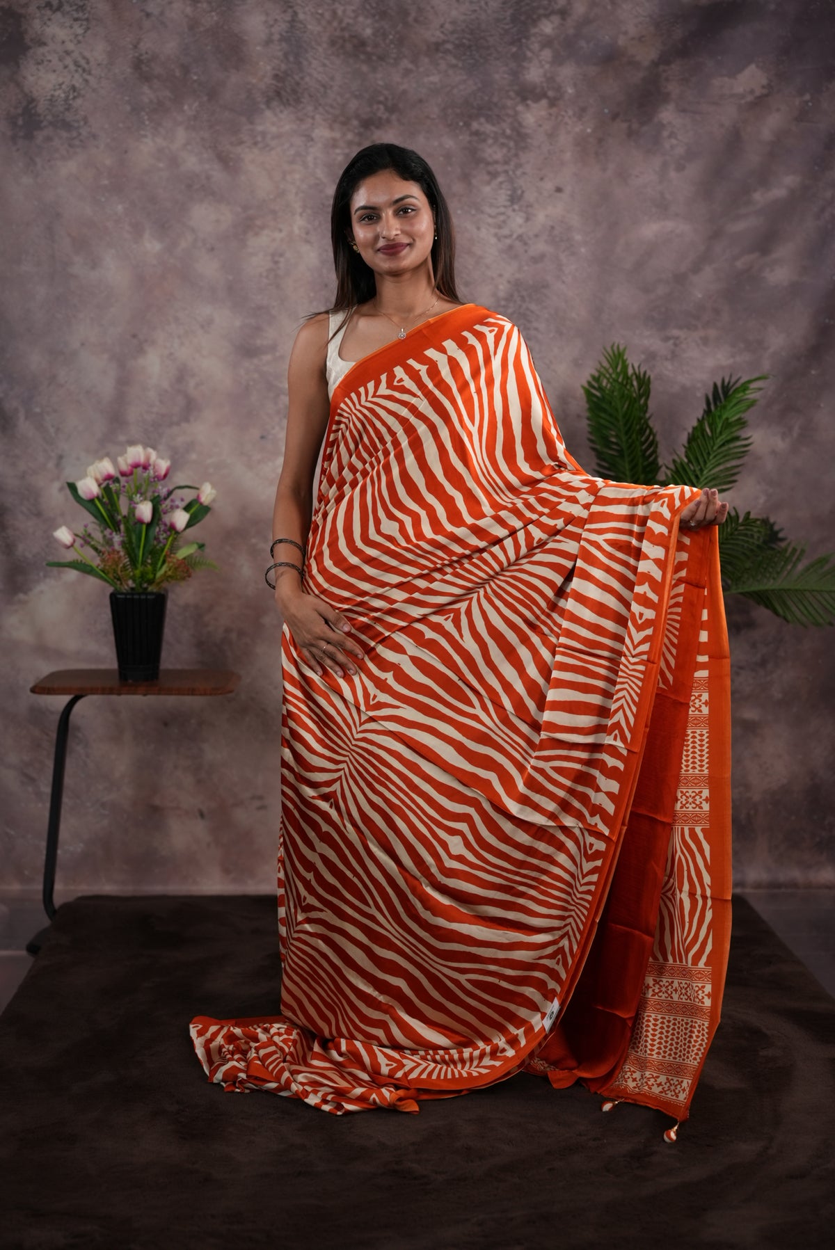 Orange Colour satin model saree featuring Zibra print on body. Ajrak & zibra print on pallu with jhumka tassels, comes with contrast plain blouse piece.