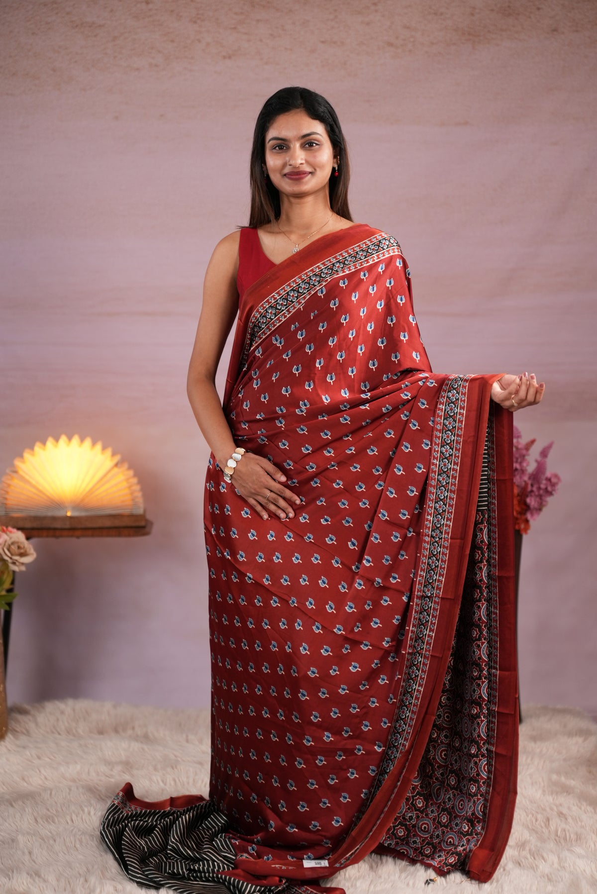 Coffee Brown and Black colour satin modal saree featuring stripes on the body, Ajrakh prints on the border & polka dots with jhumka tassels on the pallu, paired with a matching Ajrakh printed blouse piece.