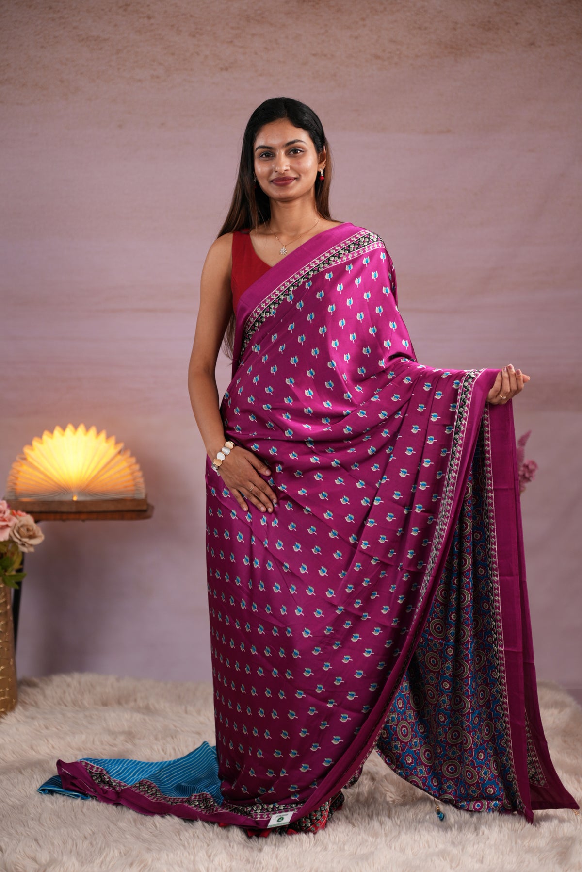 Purple and Sky Blue colour satin modal saree featuring stripes on the body, Ajrakh prints on the border & polka dots with jhumka tassels on the pallu, paired with a matching Ajrakh printed blouse piece.